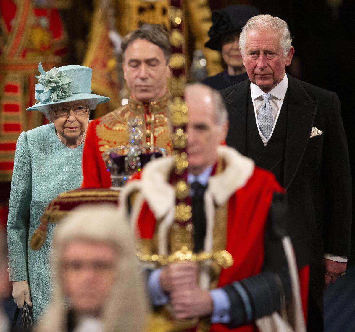 Britain's Queen Elizabeth II walks with Prince Charles through the Royal Gallery before delivering the Queen's Speech at the state opening of Parliament in London on Dec. 19, 2019.