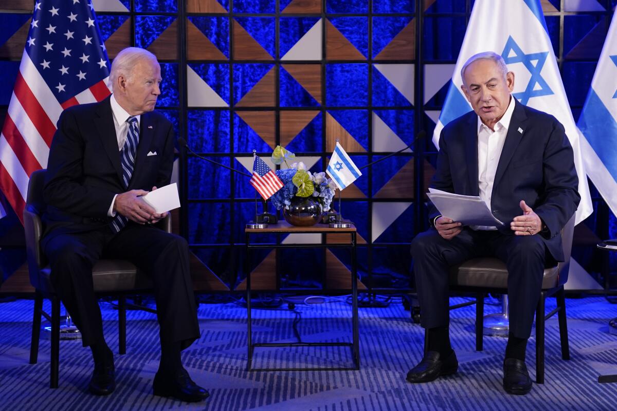 President Biden and Prime Minister Benjamin Netanyahu talk while seated on a stage