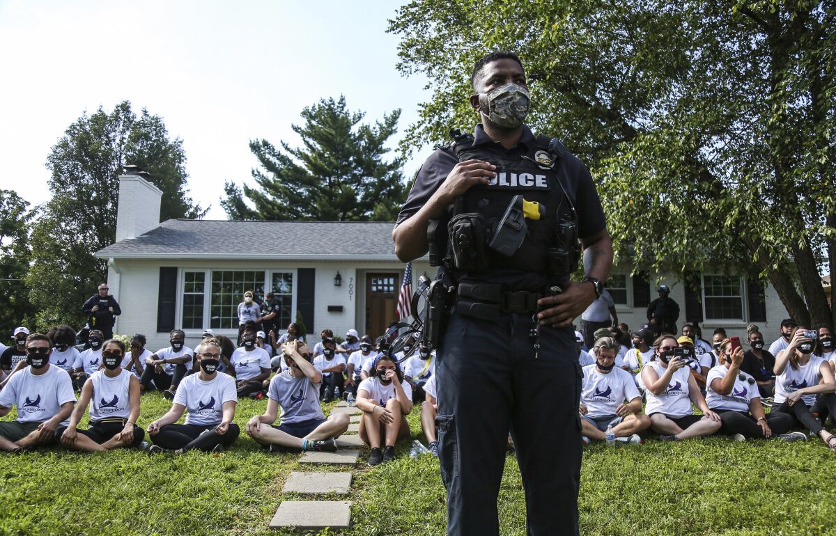 Officers keep watch as protesters sit outside the home of Kentucky Attorney General Daniel Cameron