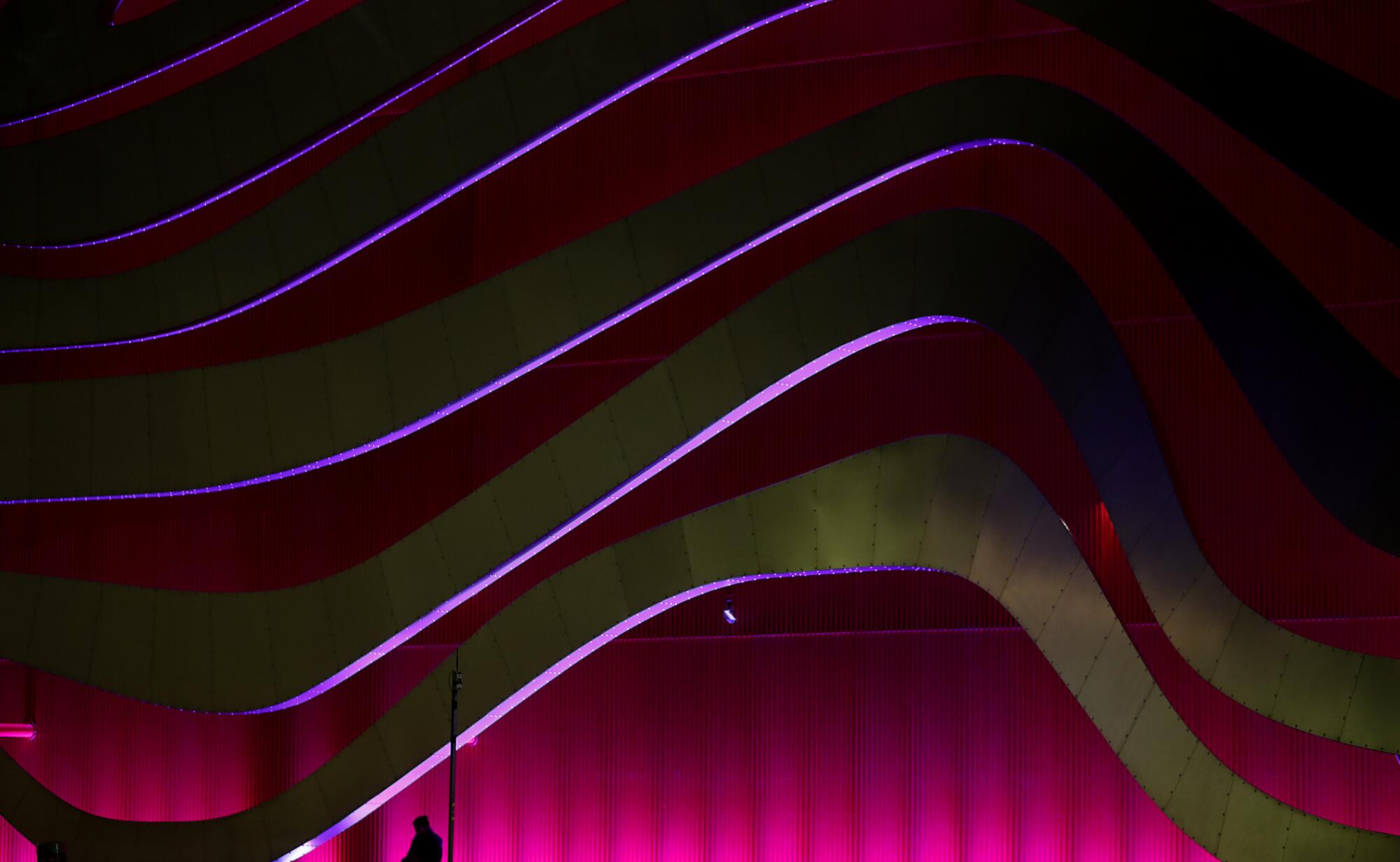 A lone commuter waits for a bus outside the Petersen Automotive Museum along Wilshire Boulevard in Midtown. 