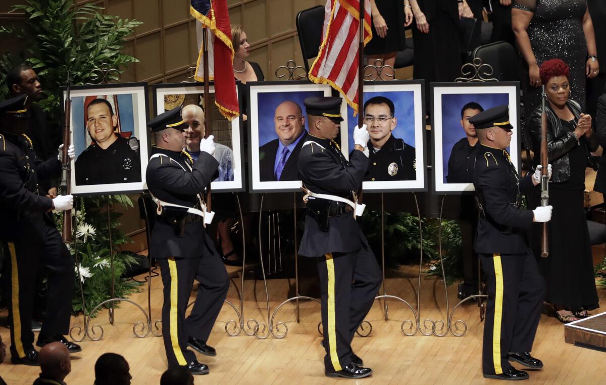 An honor guard passes photos of the fallen police officers during a memorial service at the Morton H. Meyerson Symphony Center, Tuesday, July 12, 2016, in Dallas.