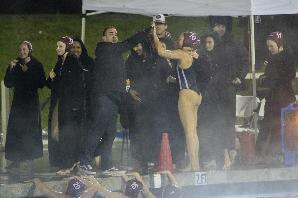 Laguna Beach coach Ethan Damato, left, high-fives Emma Lineback after beating Foothill in a CIF Southern Section Division 1 semifinal playoff match on Feb. 13 at Irvine’s Woollett Aquatics Center.