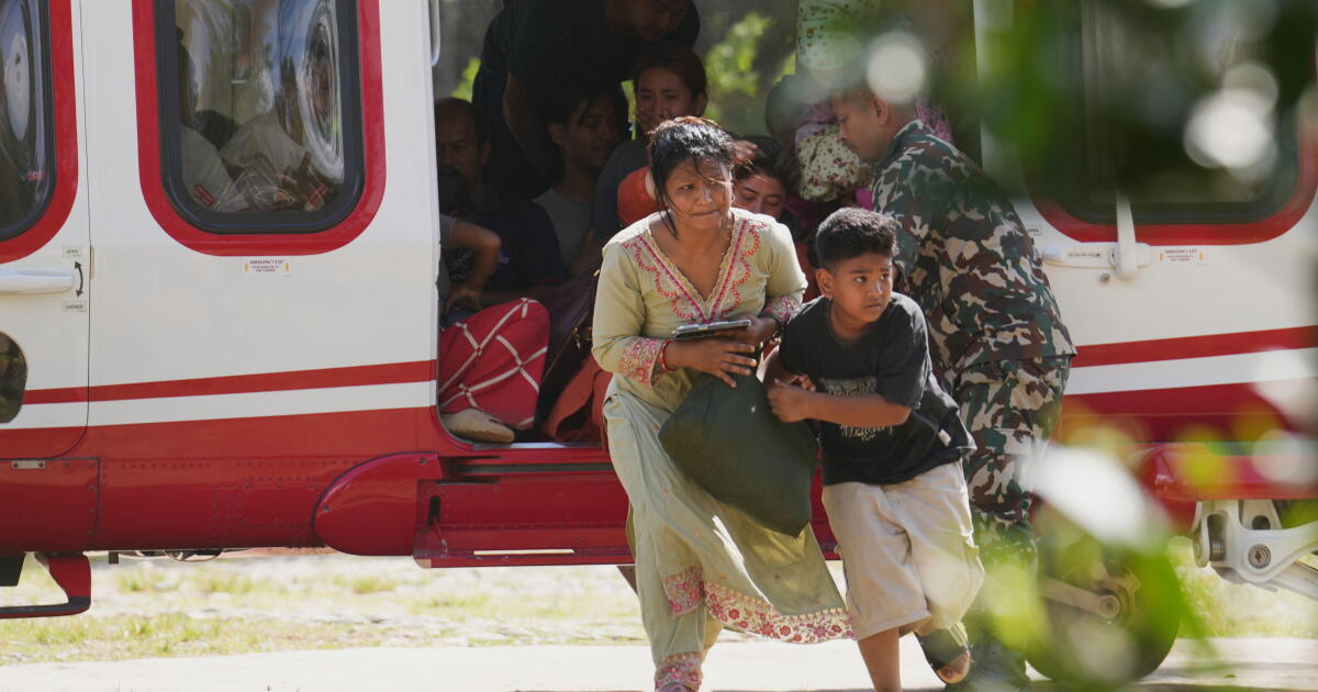 Photo: Los Angeles Times Army soldiers help a family disembark from a helicopter after they are rescued from an area affected by flash flooding in