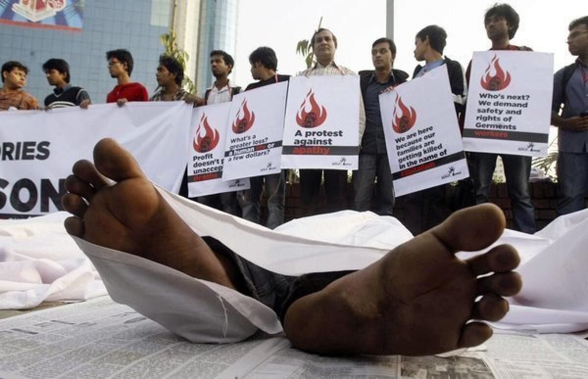 Bangladeshi protesters hold placards while others pose as dead bodies in a demonstration condemning the death of workers in a fire at a garment factory in Dhaka, Bangladesh.