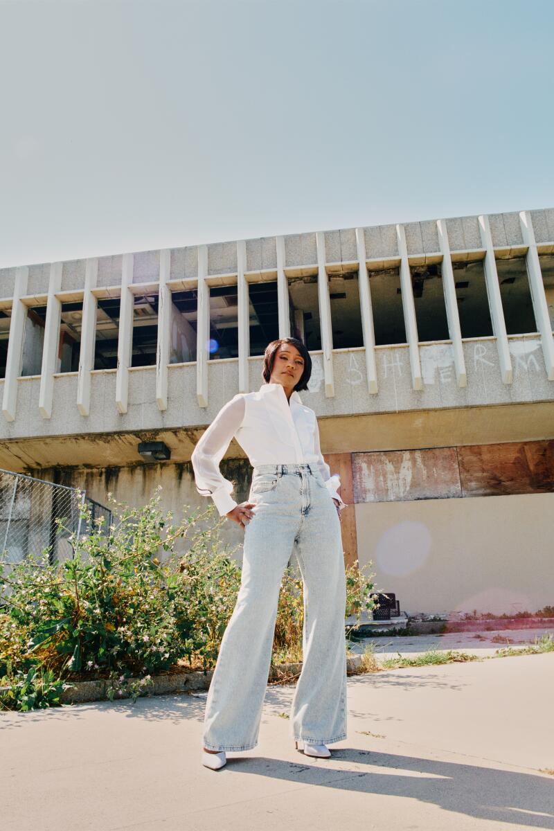 Tiffany Haddish stands in front of a white building on a sunny day