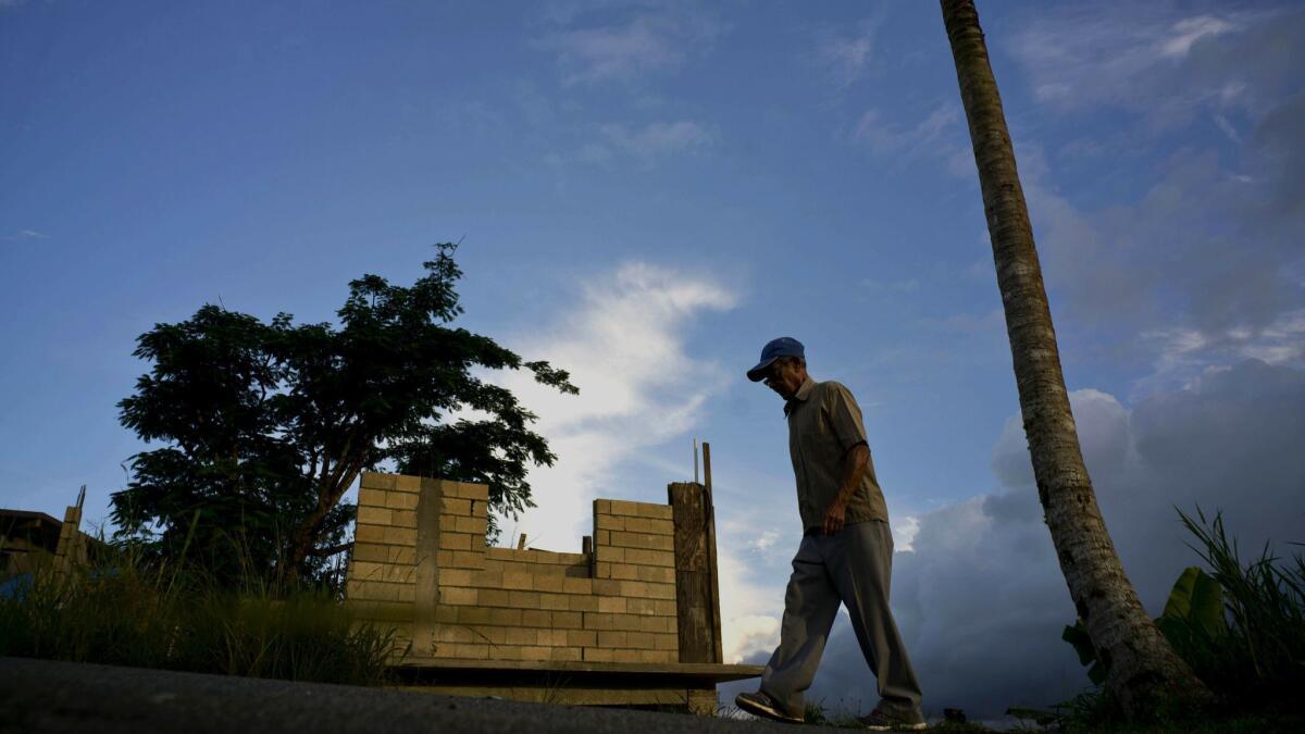 Ramon Alicea Burgos walks past his partially rebuilt home in the mountain town of Barranquitas, Puerto Rico, on Sept. 9, 2018.