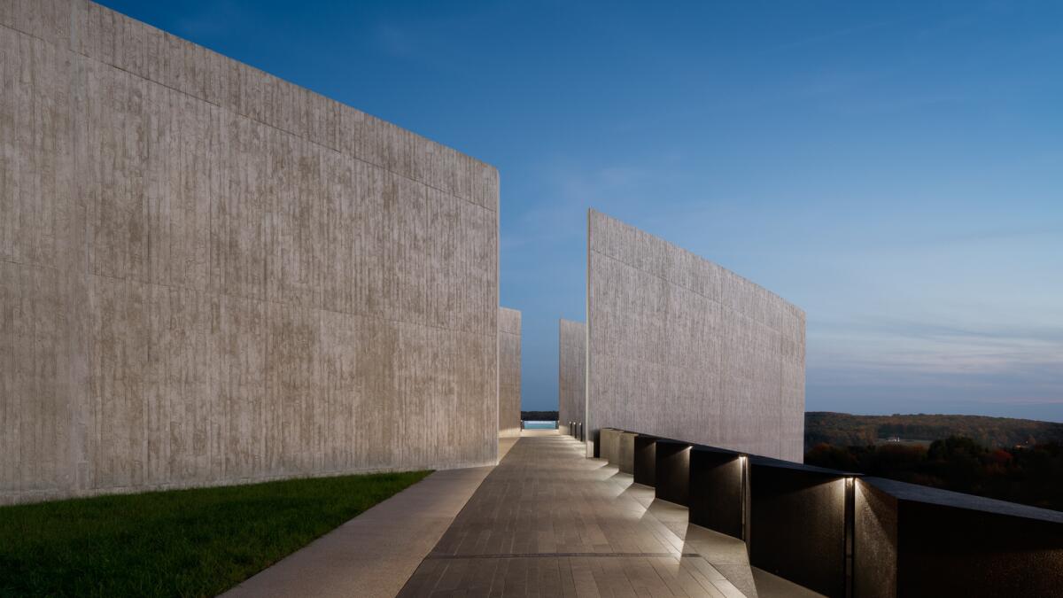 A pair of parallel concrete walls are bisected by a pedestrian path in the light of dusk
