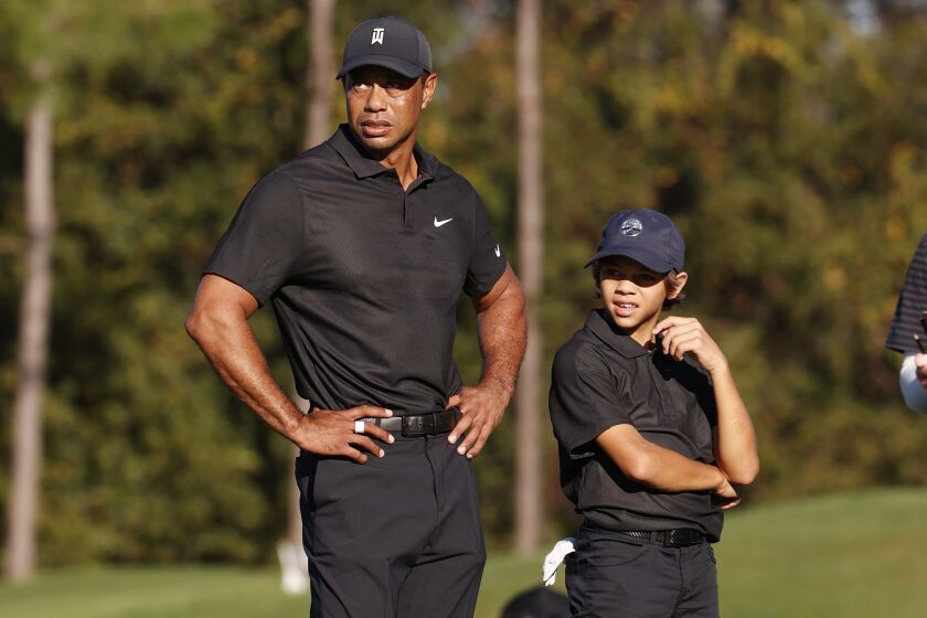 Tiger Woods, left and his son Charlie Woods, watch play during the Pro-Am round of the PNC Championship golf tournament Friday, Dec. 17, 2021, in Orlando, Fla. Woods is back playing after getting injured in a car accident. He is paired with his son Charlie during the tournament. (AP Photo/Scott Audette)