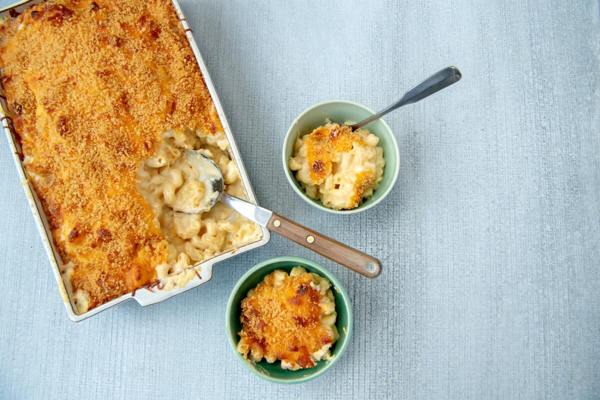 Macaroni and cheese served in two small bowls next to a casserole dish full of it.