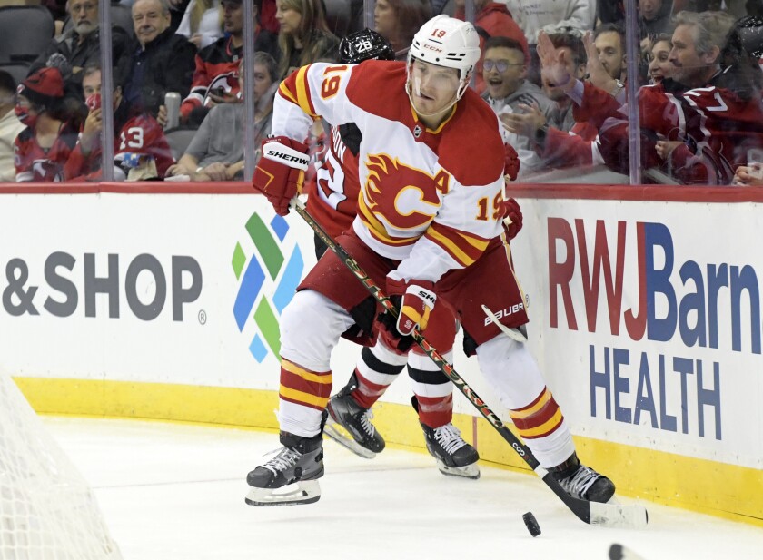 FILE - Calgary Flames left wing Matthew Tkachuk (19) looks to pass the puck during the second period of an NHL hockey game against the New Jersey Devils Tuesday, Oct. 26, 2021, in Newark, N.J. Matthew Tkachuk is being traded to the Florida Panthers, part of a blockbuster that sends Jonathan Huberdeau to the Calgary Flames in a swap of players who are each coming off the best season of their careers, a person with knowledge of the negotiations said Friday night, July 22, 2022. (AP Photo/Bill Kostroun, File)