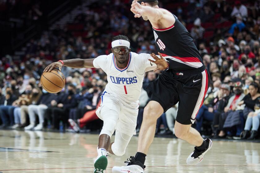 Los Angeles Clippers guard Reggie Jackson, left, dribbles around Portland Trail Blazers center Cody Zeller during the first half of an NBA basketball game in Portland, Ore., Monday, Dec. 6, 2021. (AP Photo/Craig Mitchelldyer)