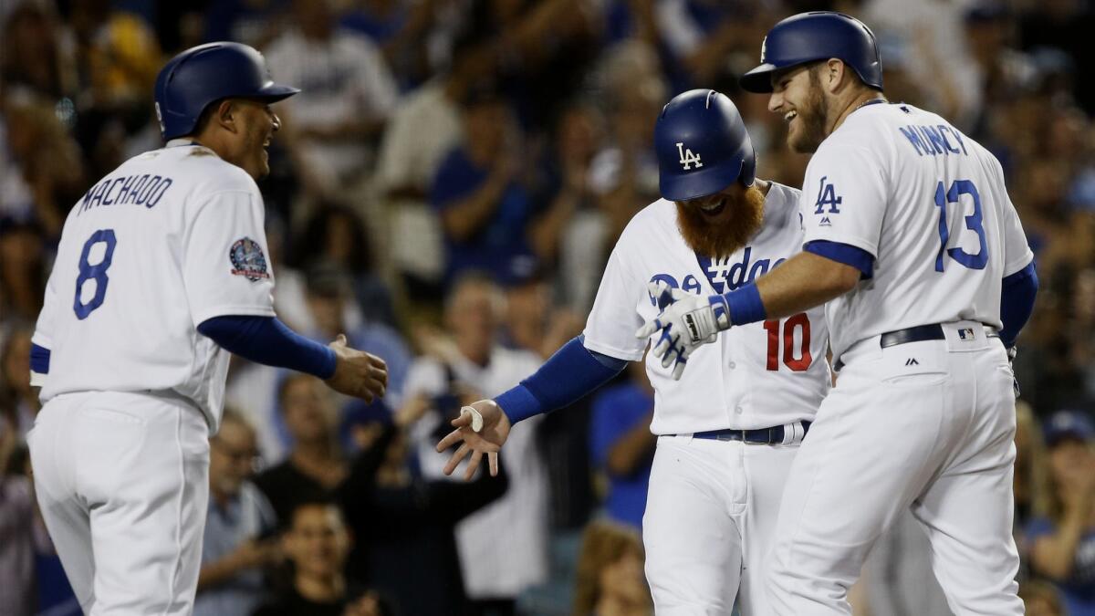 Dodgers' Max Muncy, right, celebrates his three RBI home run to score both Manny Machado, left, and Justin Turner against the Colorado Rockies during the third innin.