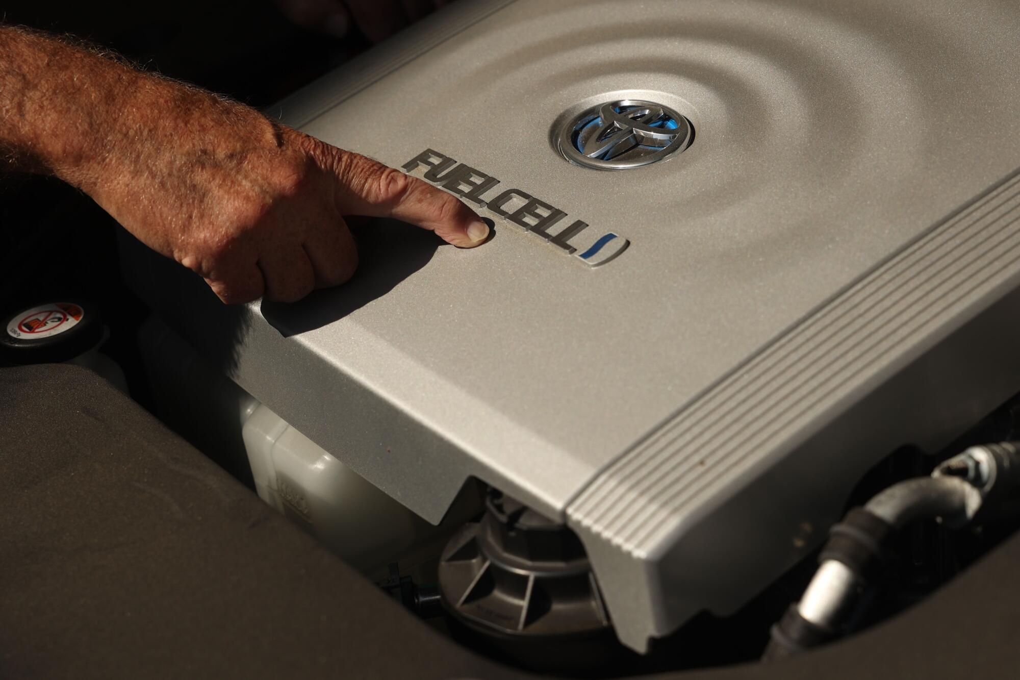 A main points at the Toyota fuel cell badging on his car. 