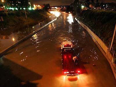An emergency vehicle navigates a flooded Hollywood Freeway Monday night, near Santa Monica Boulevard. The freeway was closed in both directions for more than three hours after a cloudburst and clogged drains left about two feet of water pooling on the lanes.
