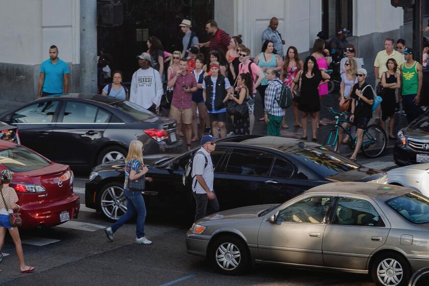 Pedestrians make their way through a maze of cars in the crosswalk at the intersection of Hollywood and Highland boulevards on June 16. This intersection is one of the worst for pedestrian collisions.