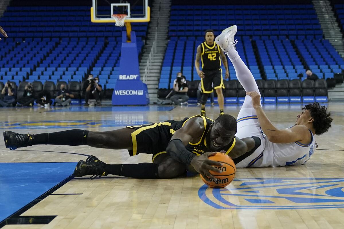 Oregon's Franck Kepnang reaches for the ball after colliding with UCLA guard Jules Bernard.