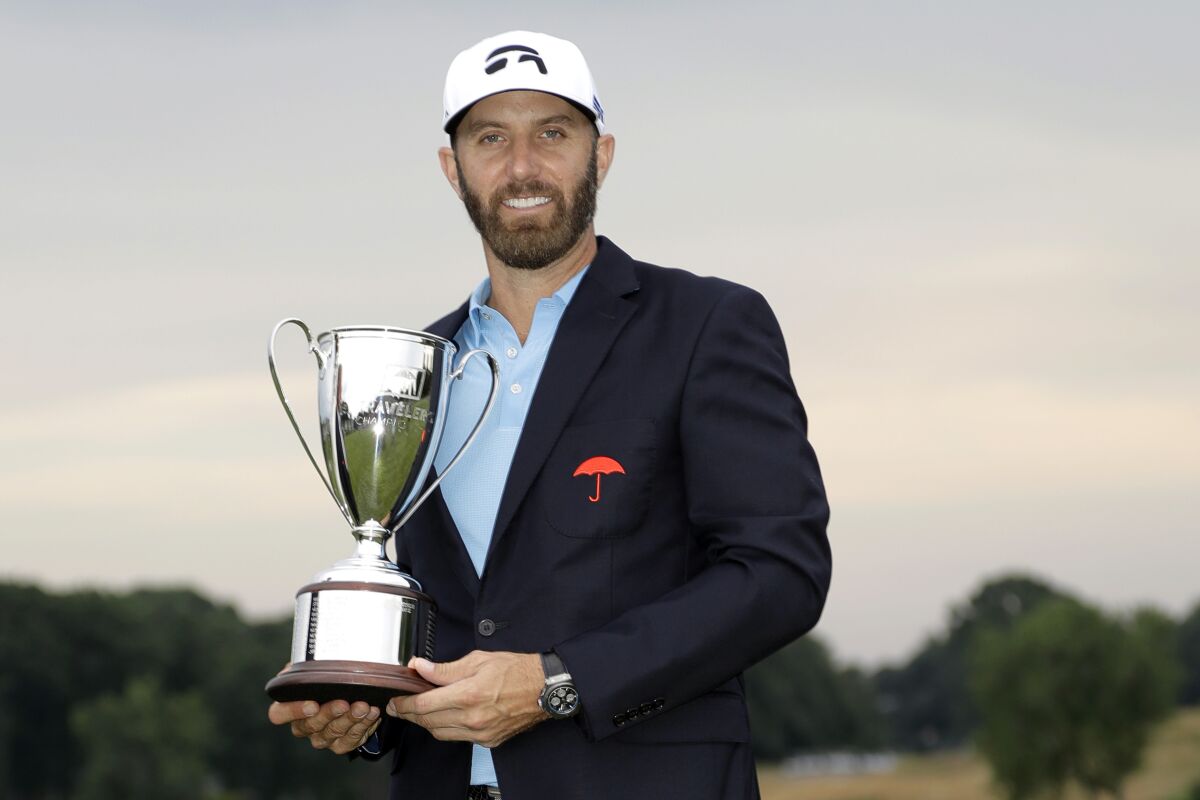 FILE — In this June 28, 2020, file photo, Dustin Johnson poses with the trophy after winning the Travelers Championship golf tournament at TPC River Highlands, Sunday, in Cromwell, Conn. Johnson says it was surreal sinking the final putt to win last year's Travelers Championship with fewer than 40 spectators politely clapping instead of the thousands that usually fill the bowl surrounding the 18th green at TPC River Highlands. (AP Photo/Frank Franklin II, File)