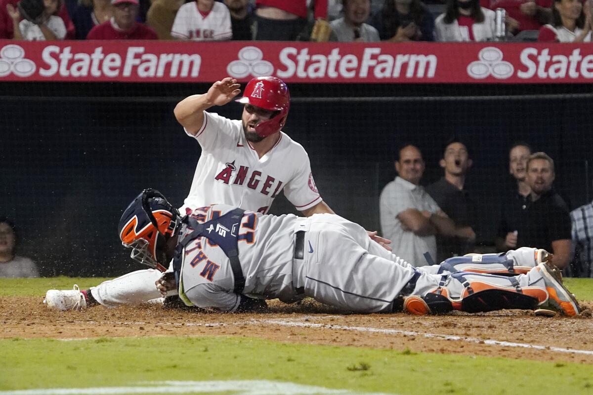 Angels' Jack Mayfield is tagged out at home by Houston Astros catcher Martin Maldonado while trying to score.