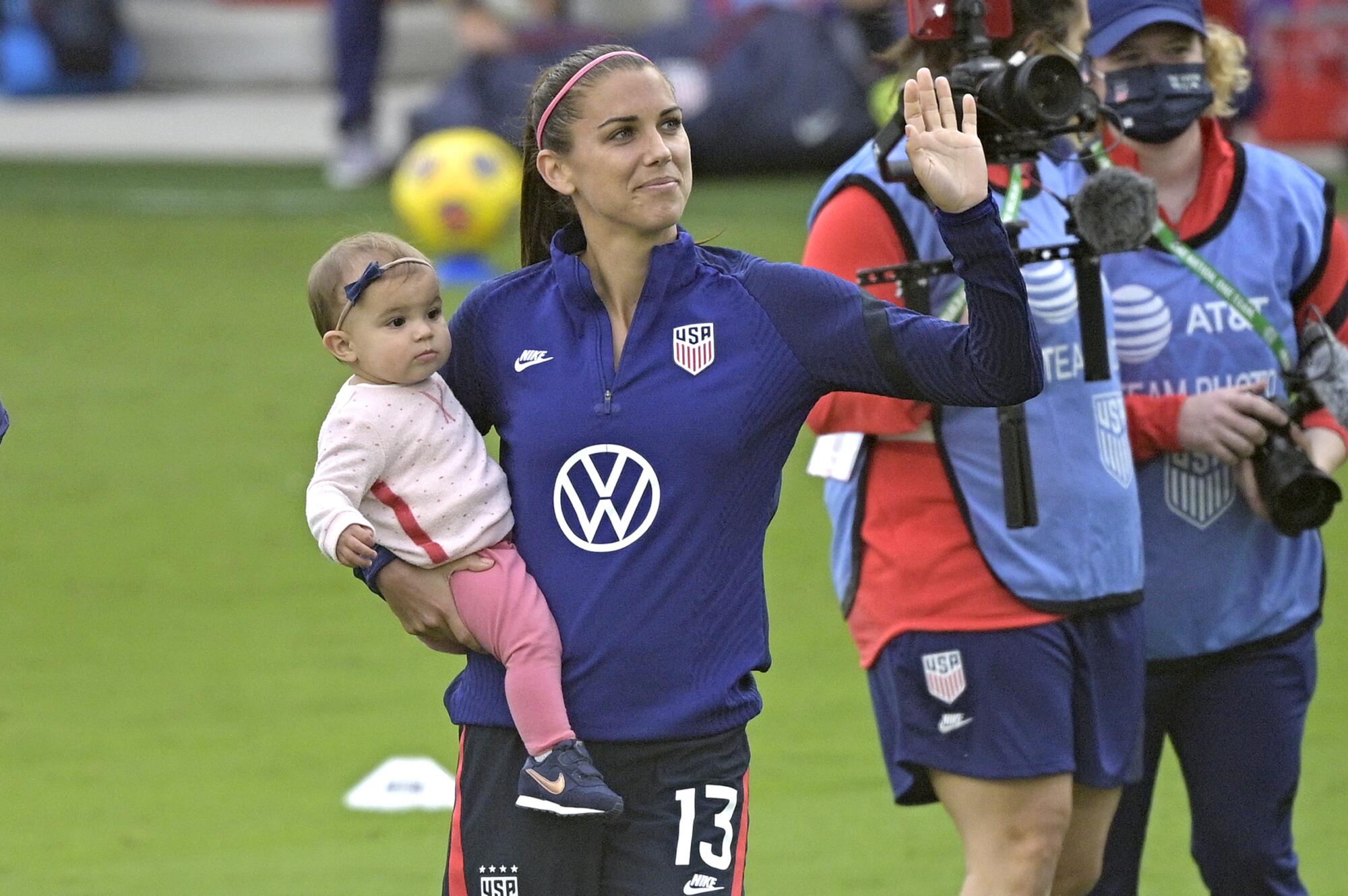 U.S. forward Alex Morgan (13) waves to fans while holding her daughter, Charlie Elena Carrasco,