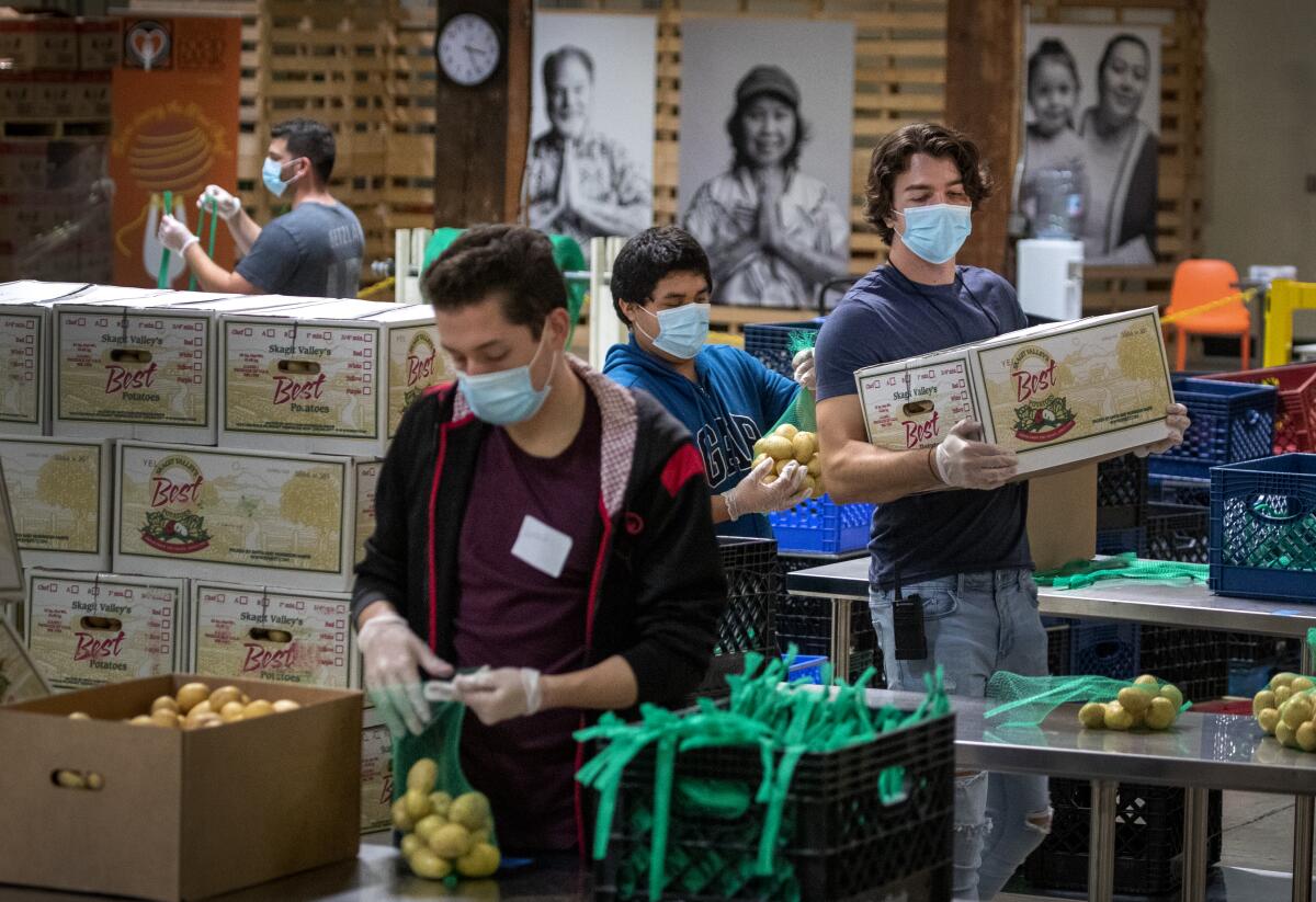 Jose Secundino and other temporary employees in face masks pack boxes at an Orange County food bank.