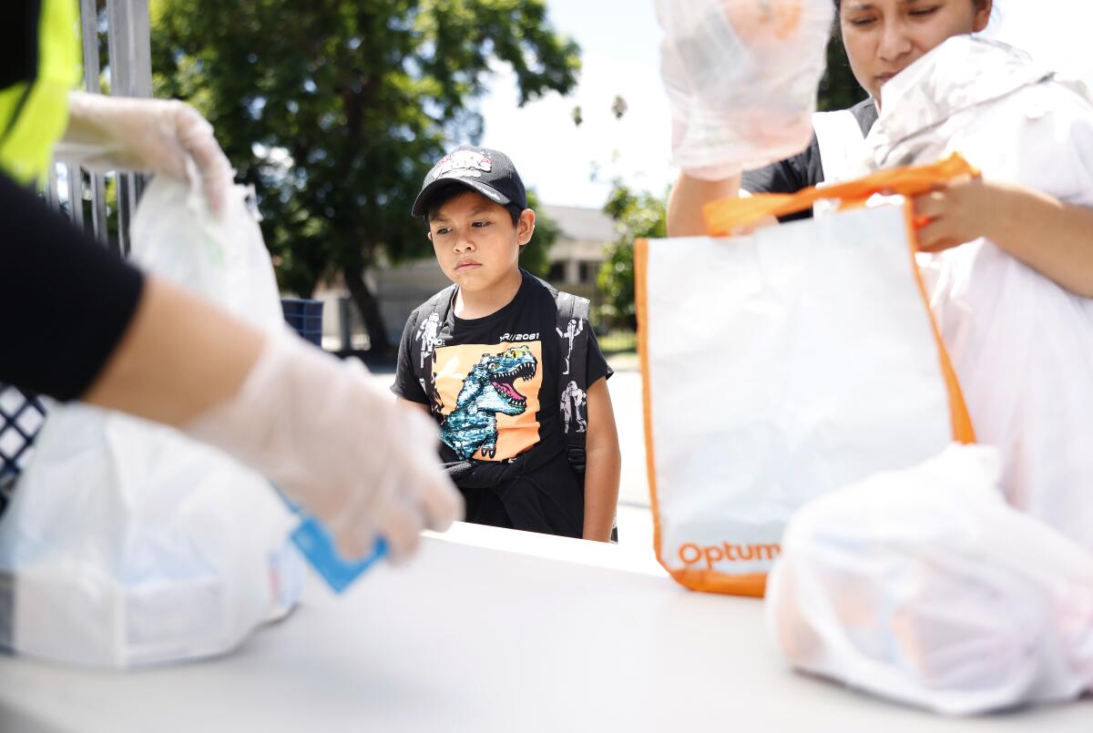 Renato Ramirez, 8 and his mom Daniela Fuentes pick up meals at a Grab and Go food site at Fremont High School.