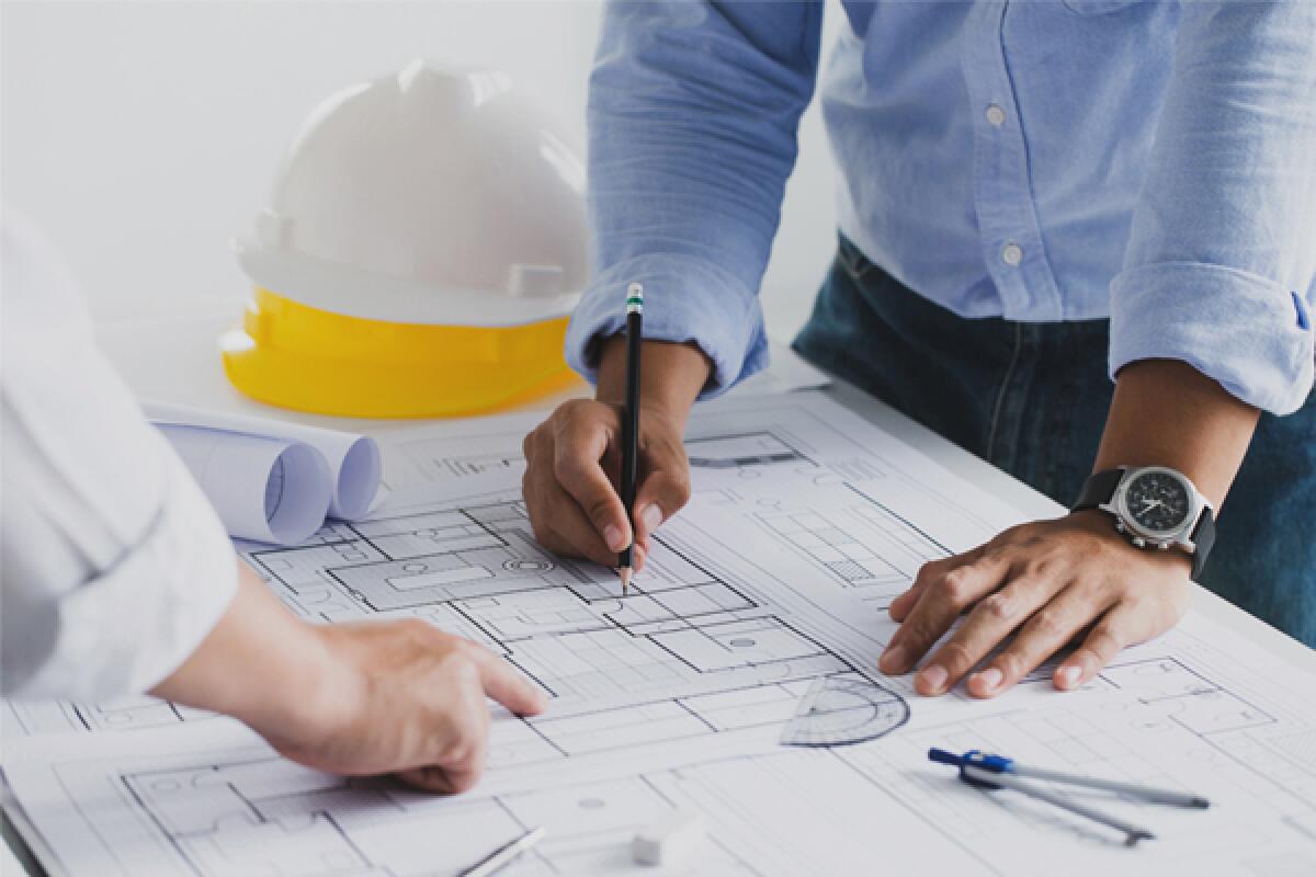 A person sketches on a construction blueprint
