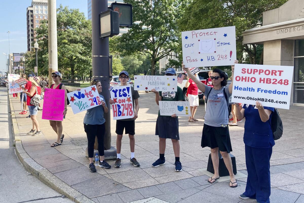 People line a street corner, carrying posters; one says "Vote Yes 248."