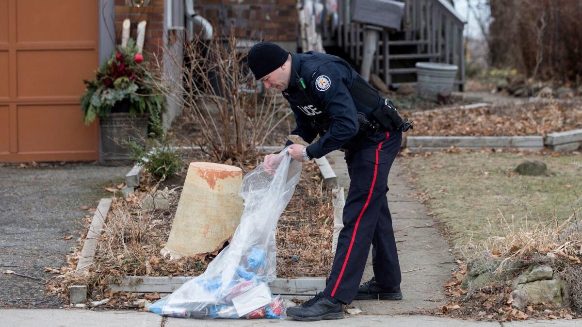 A police officer investigates outside a Toronto home serviced by landscaper Bruce McArthur, who is accused of killing at least five people and is suspected of more slayings.