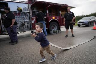 Noah Hernandez, 3, carries a fire hose while attending a National Night Out event with his parents in the Colony Ridge development Tuesday, Oct. 3, 2023, in Cleveland, Texas. The booming Texas neighborhood is fighting back after Republican leaders took up unsubstantiated claims that it has become a magnet for immigrants living in the U.S. illegally and that cartels control pockets of the neighborhood. (AP Photo/David J. Phillip)