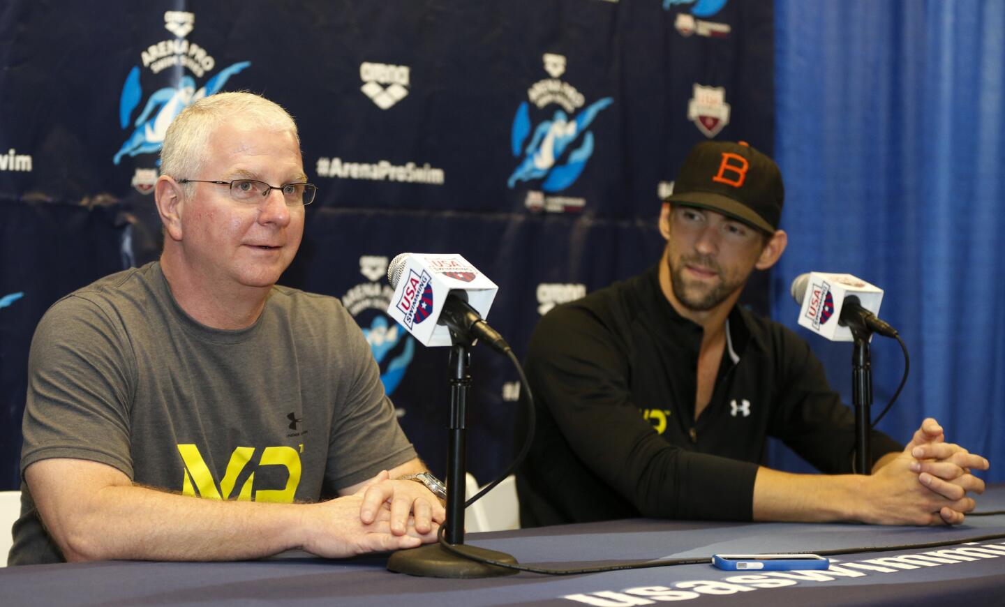 Bob Bowman, left, answers a question as Michael Phelps looks on at a news conference at the Arena Pro Swim Series swim meet in Charlotte, N.C.