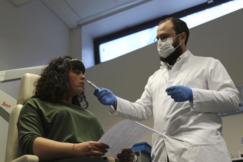El doctor Clair Vandersteen le hace oler distintos aromas a Gabriella Forgione en una clínica de Niza que estudia la pérdida del olfato por parte de pacientes del COVID-19. Foto del 8 de febrero del 2021. (AP Photo/John Leicester)