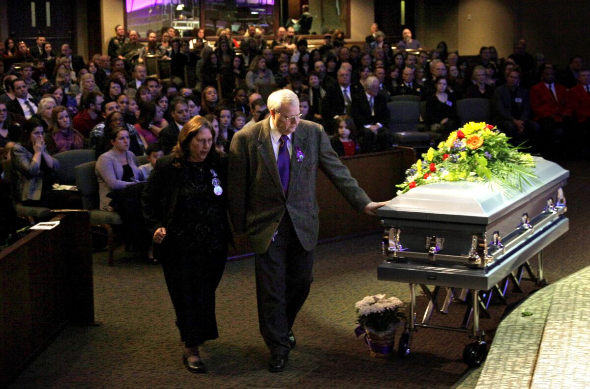 Chuck Cox touches the casket holding his grandsons, Charles and Braden, as he walks with his wife, Judy, during a funeral service in Tacoma, Wash.