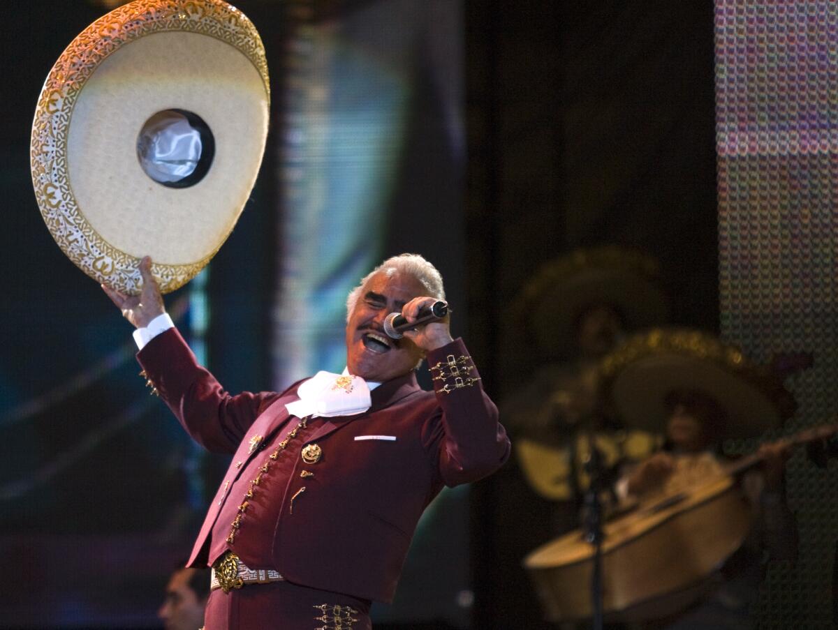 A man waving a sombrero and singing into a microphone