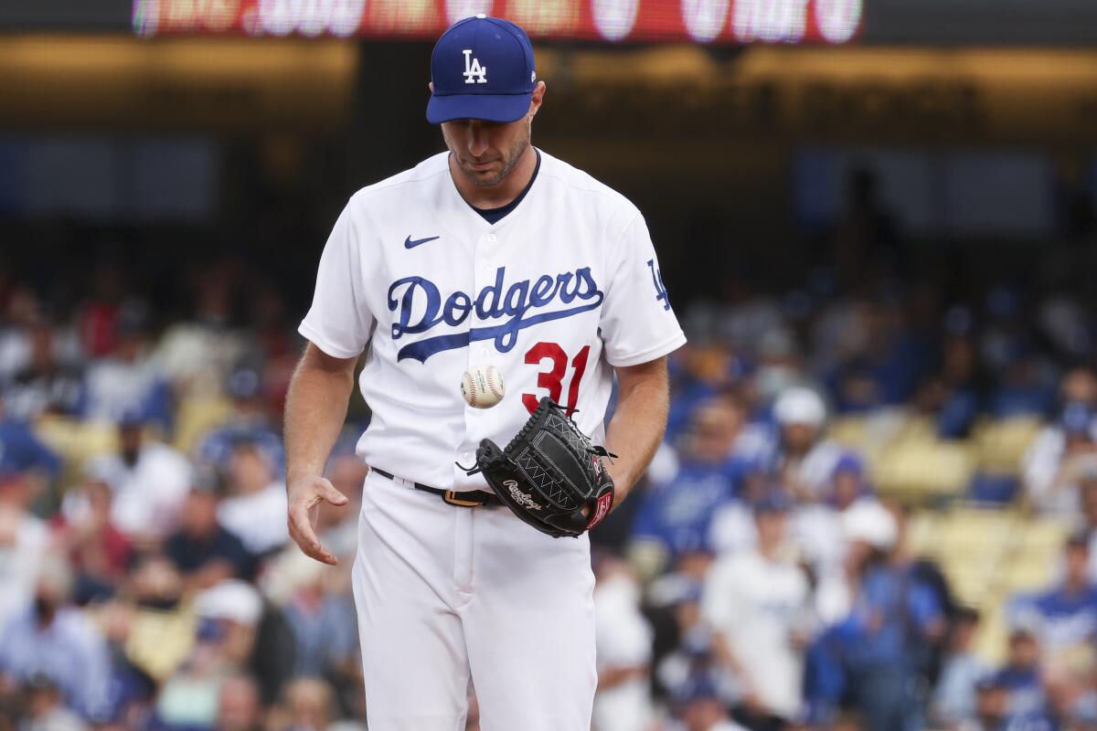 Dodgers starting pitcher Max Scherzer tosses the ball on the mound.