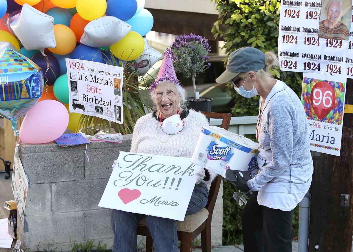Maria Siani of Laguna Beach laughs as a neighbor delivers a package of tissue during a drive-by surprise party for Siani's 96th birthday.