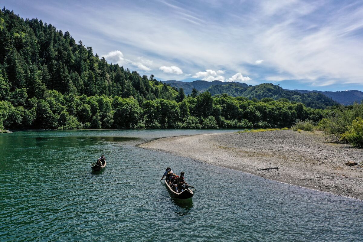 Two canoes paddle along a river.