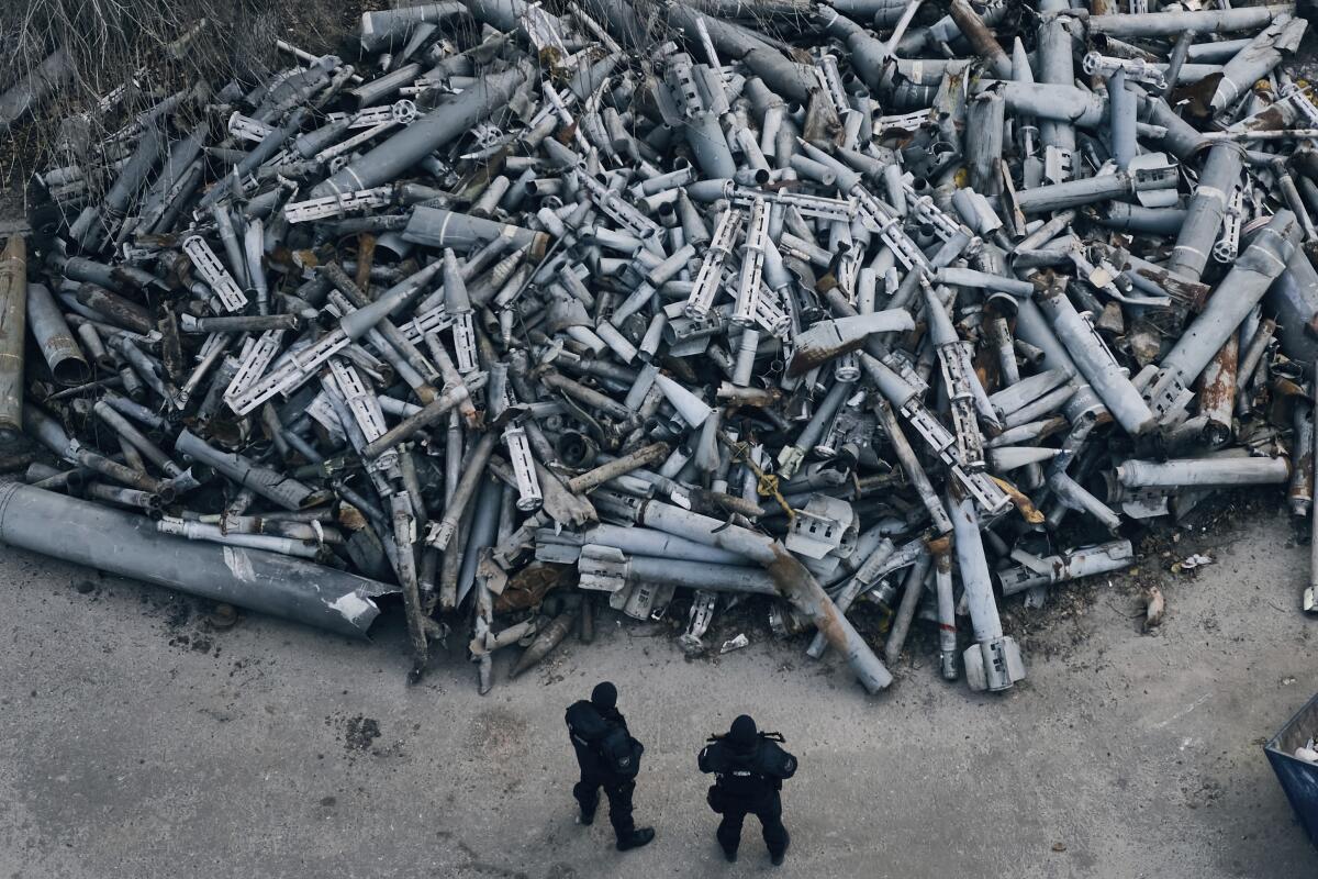 Archivo - Dos policías parados frente a fragmentos recolectados de cohetes rusos 