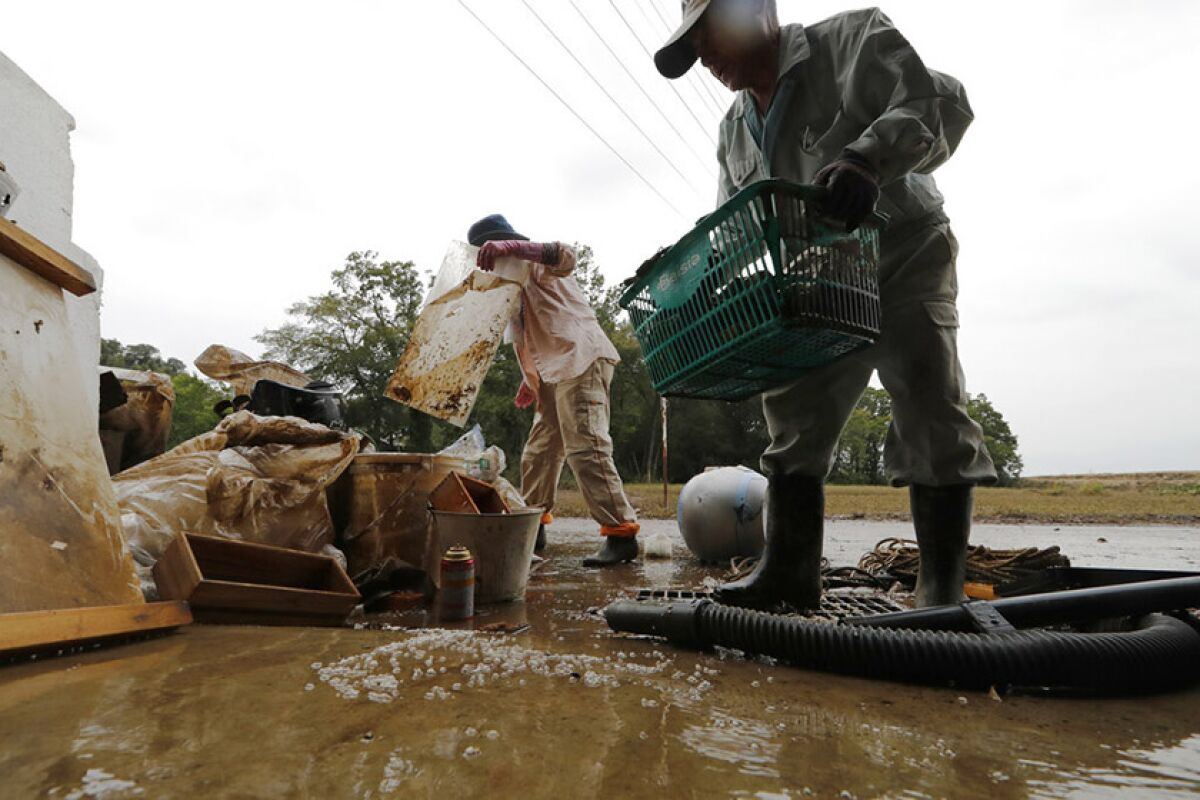 Residents Kazuo Saito, right, and Sumiko Saito clean up their home in Kawagoe City, Japan, on Monday. Typhoon Hagibis unleashed torrents of rain and strong winds Saturday.