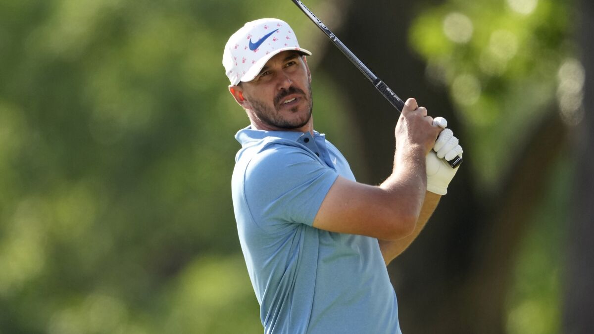 A man with a golf club watches his shot.