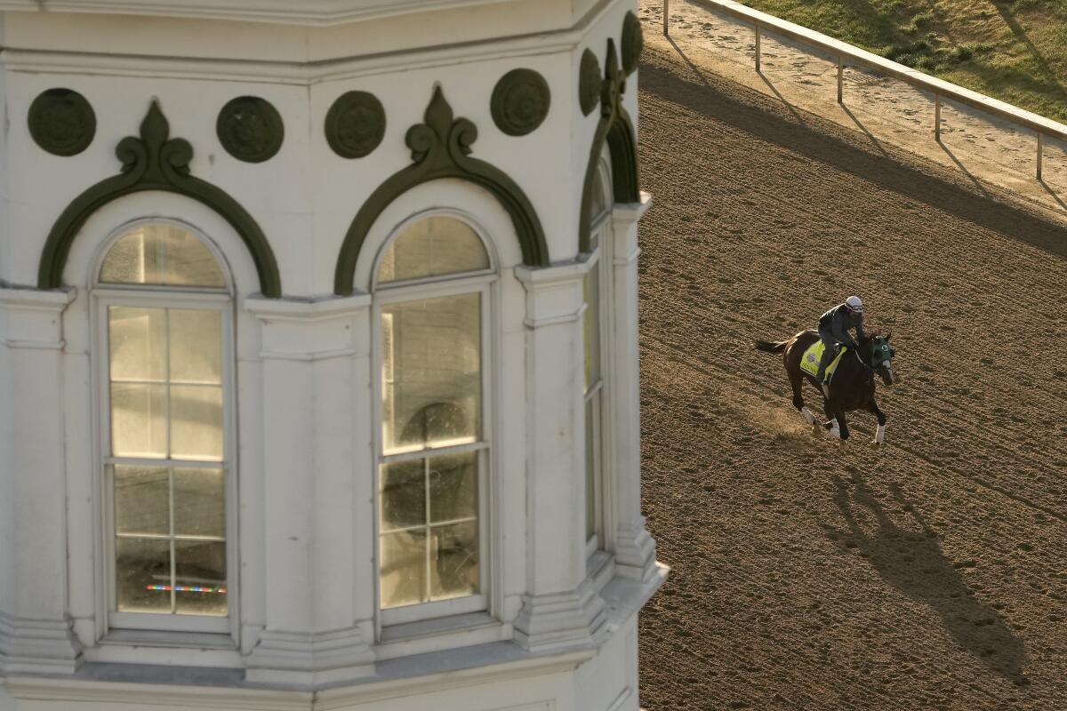 Kentucky Derby entrant Sun Thunder gallops on the track in front of a spire at Churchill Downs.