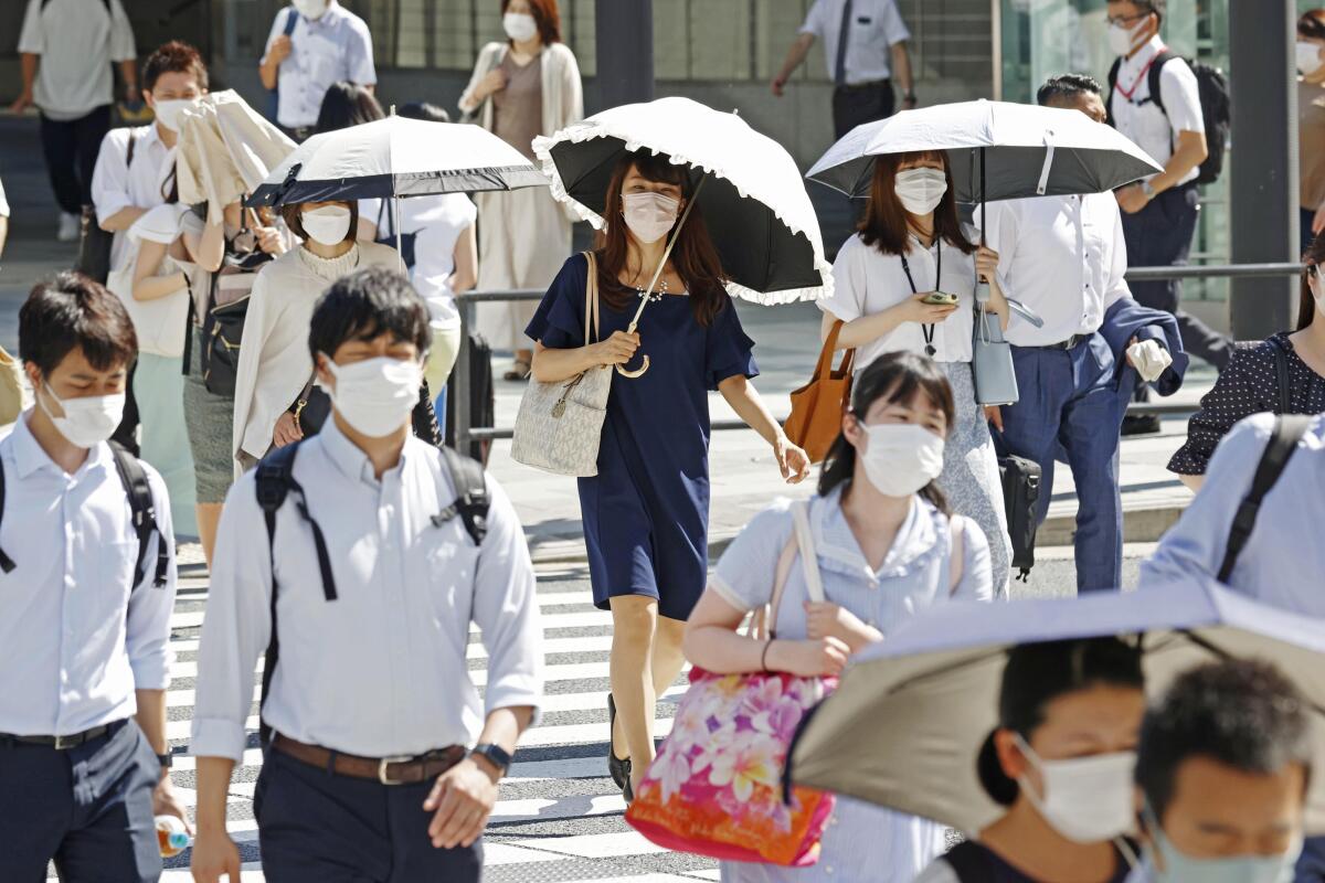 Pedestrians in Tokyo, some holding parasols