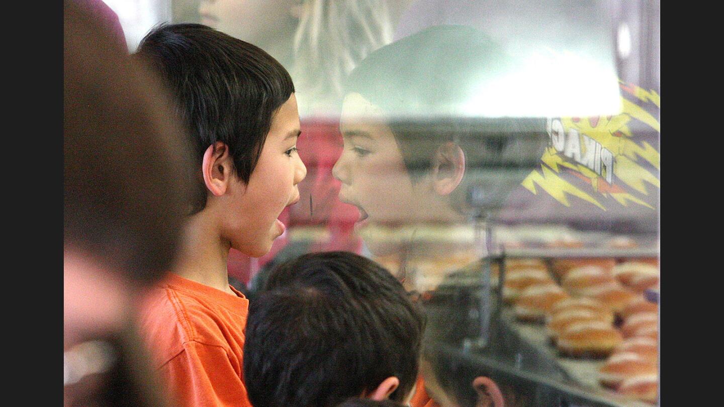 Kaiel Crume, 6, of San Marino, watches hundreds of freshly glazed doughnuts pass by on a converyor at Krispy Kreme Doughnuts in Burbank for National Doughnut Day on Friday, June 2, 2017. Everyone in line all day with the purchase of any item received a free doughnut.