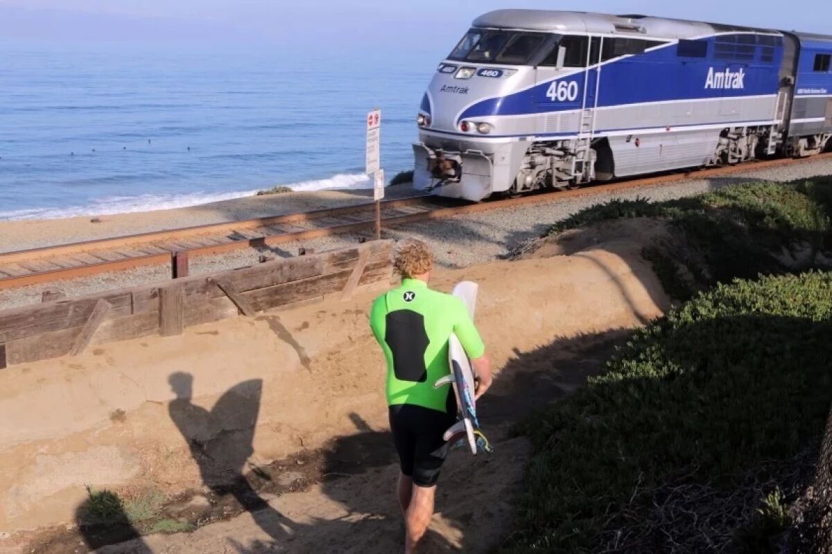 A surfer approaches the train tracks in Del Mar.