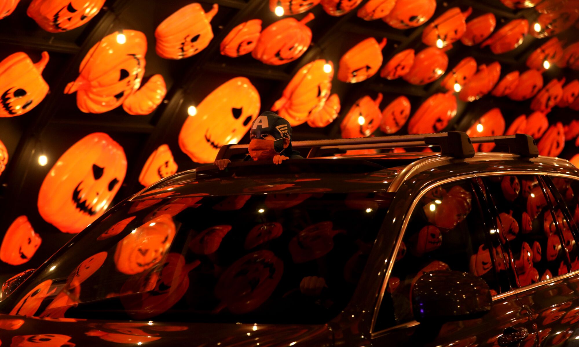 A costumed youngster rides in a car through a pumpkin tunnel at the drive-through Hauntoween LA in Woodland Hills.