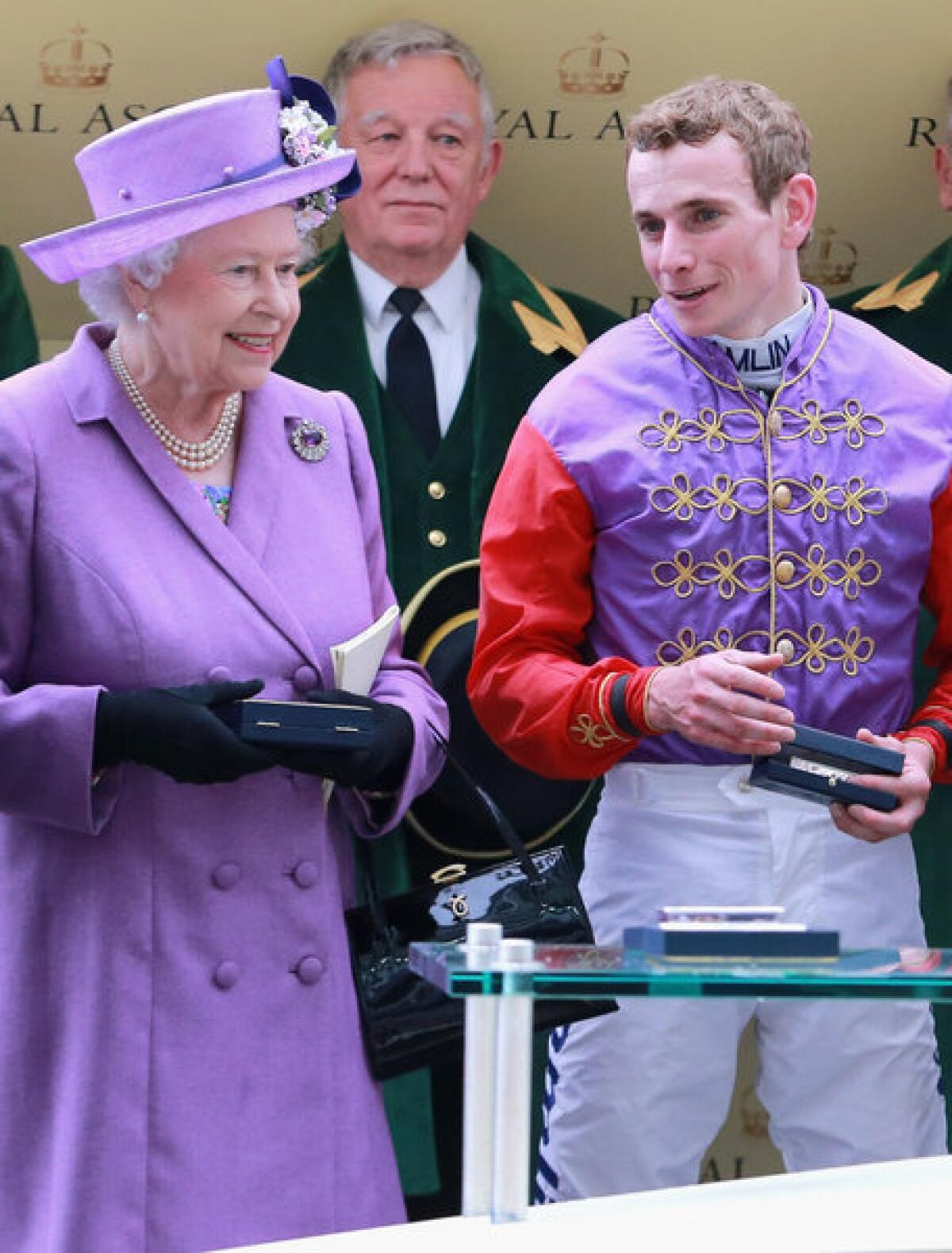 Queen Elizabeth II, dressed in purple, with jockey Ryan Moore as they celebrate winning the Gold Cup during Day 3 of the Royal Ascot in England.