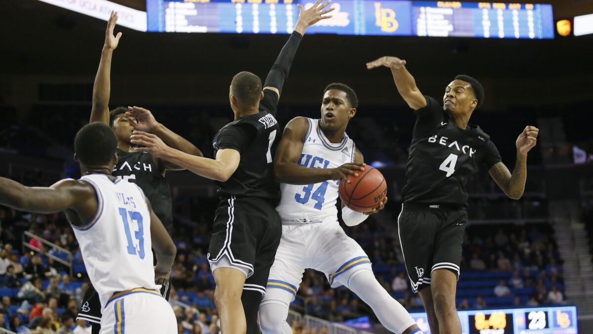 UCLA guard David Singleton, second from right, weaves through the defense of Long Beach State's Deishuan Booker, Ron Freeman, and KJ Byers, from left, while UCLA guard Kris Wilkes, front left, watches during the first half on Friday.