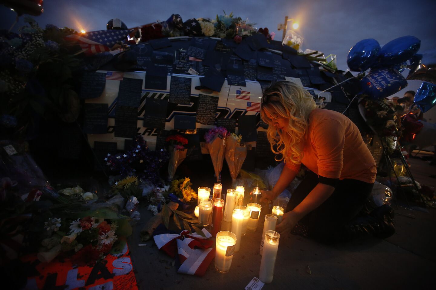 Tasha Lomoglio, of Dallas, pays her respects in front of a growing memorial at the Dallas police headquarters.
