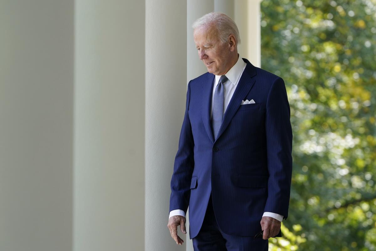 President Biden walks by columns out to the Rose Garden at the White House.