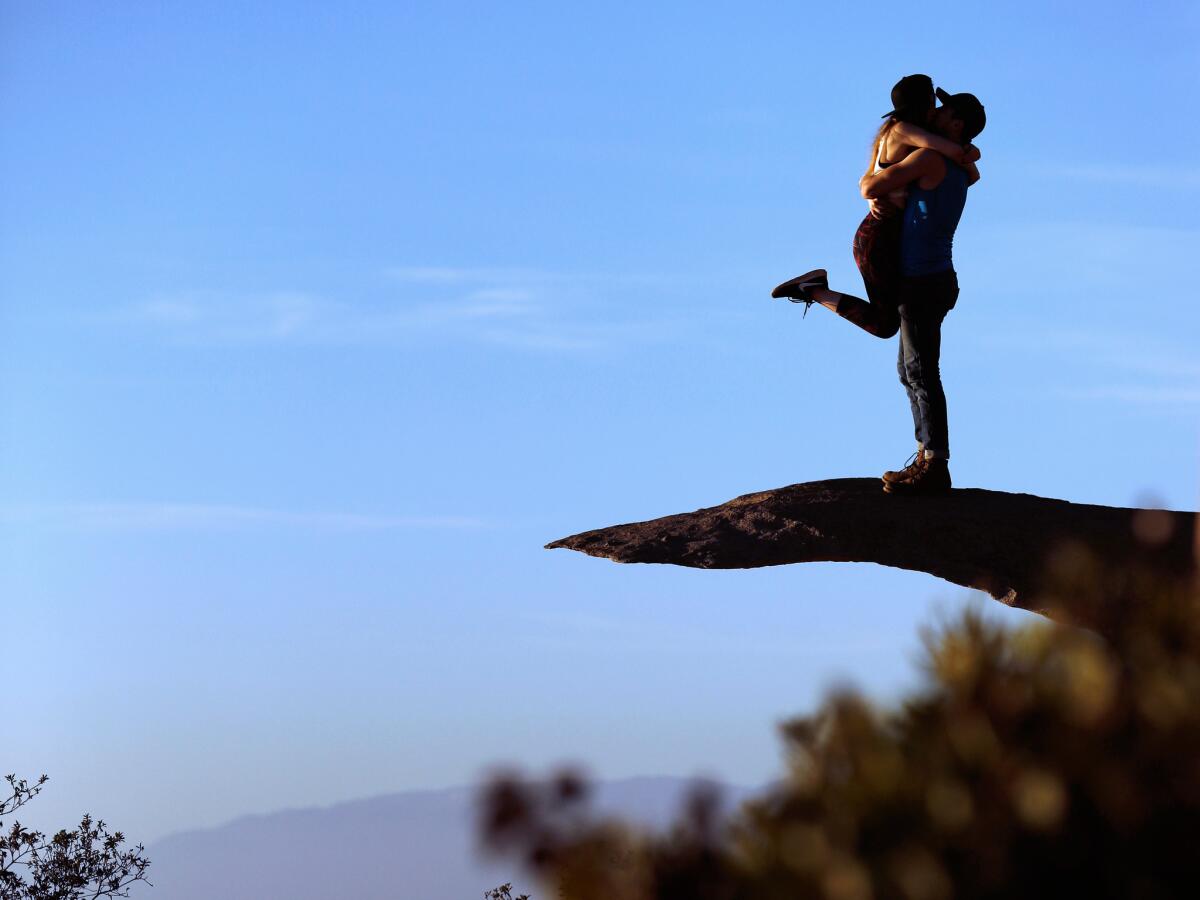 A couple shares a kiss atop the distinctive Potato Chip Rock on the Mt. Woodson trail.