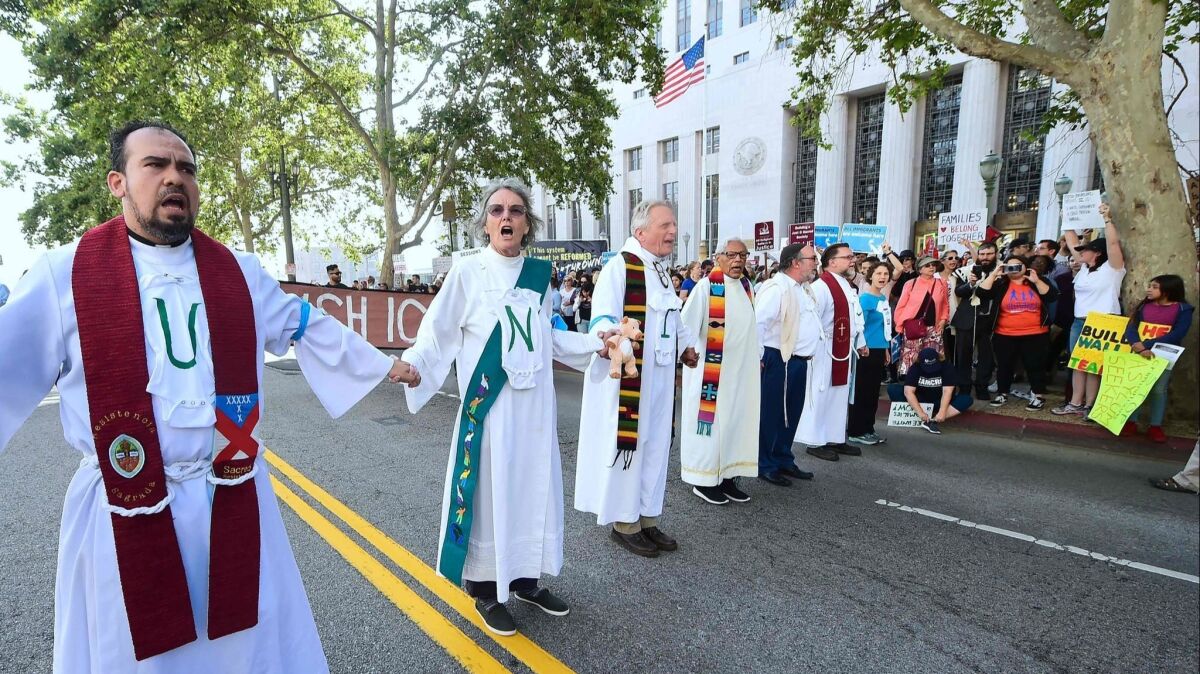 Clergy members hold hands as they block the road in front of the federal building in downtown Los Angeles to protest the Trump administration's immigration policies.